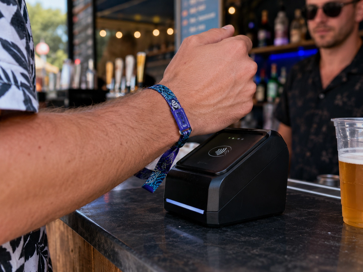 Close up of a guest tapping an RFID wristband on a cashless payment terminal at a festival bar Close up of a guest tapping an RFID wristband on a cashless payment terminal at a festival bar